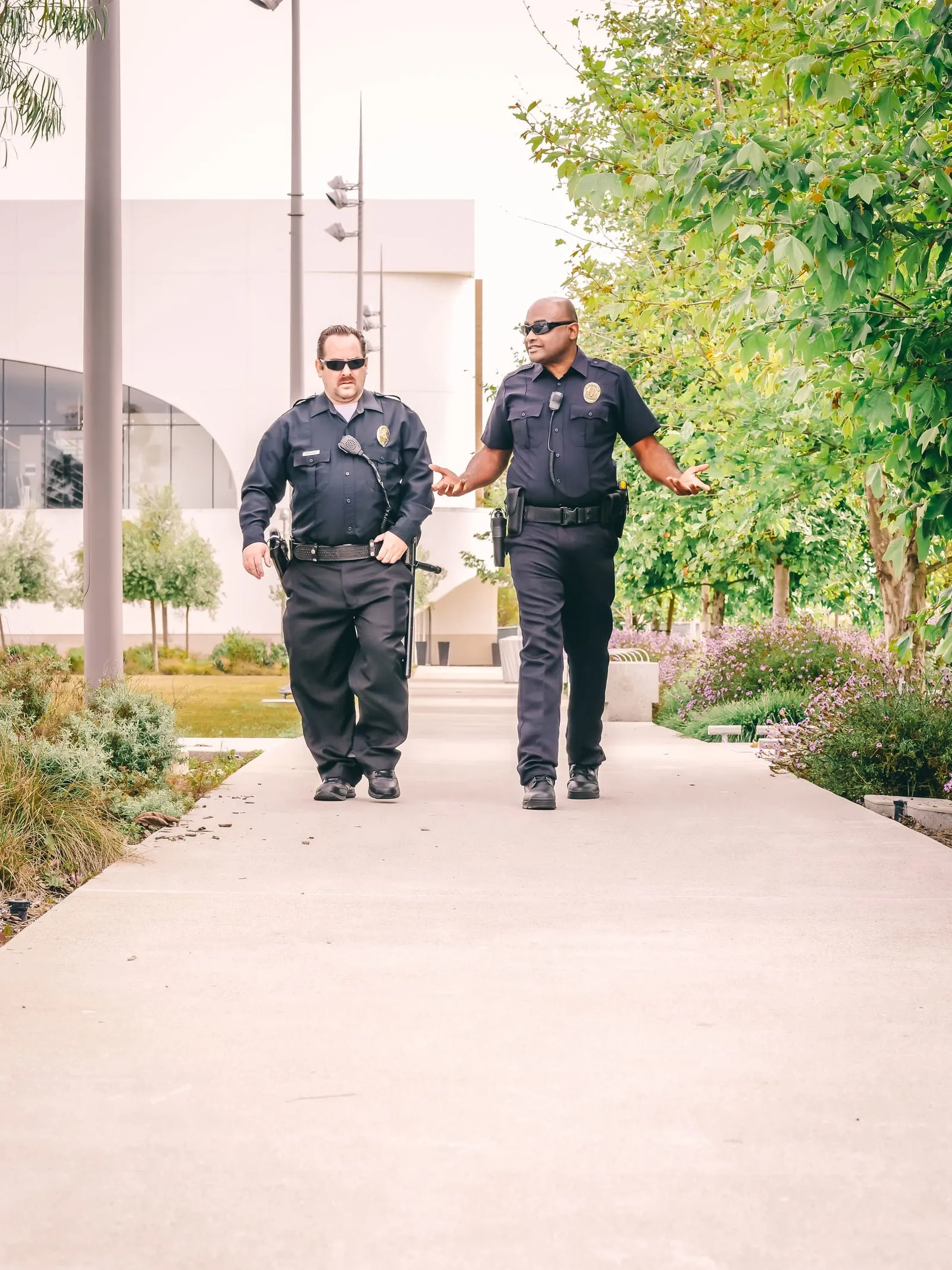 Two uniformed security officers walking and talking outside an office building.