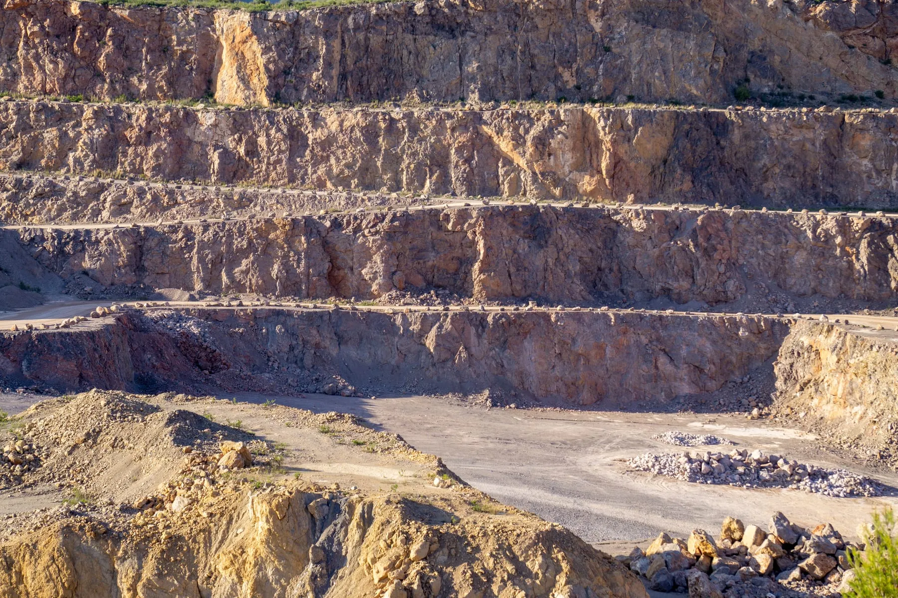 Terraced rock face of an open-pit quarry, showing the layered extraction process.